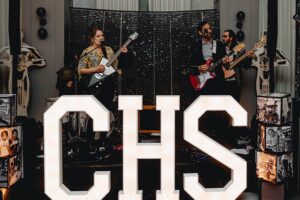 A band playing on stage in front of CHS lighted sign