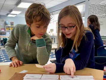 Boy and girl student pointing at math problem on a sheet together